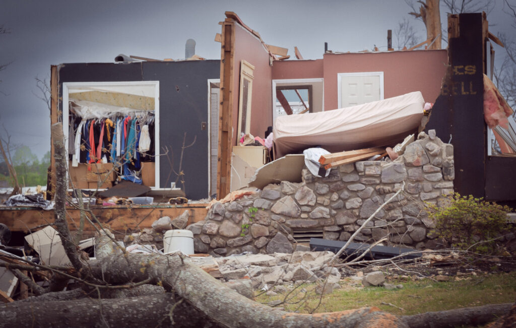 photograph of a house destroyed by a tornado on March 31, 2023 in Little Rock, Arkansas. in this image the walls and roof of the house are gone, and the contents of the rooms can be seen