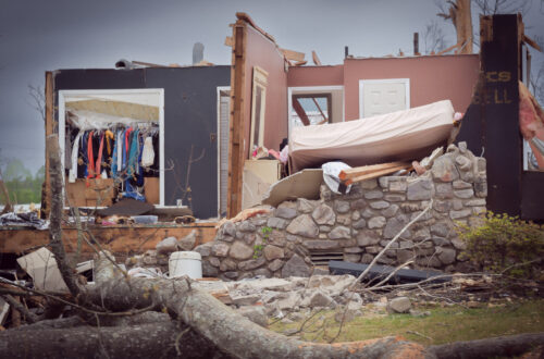 photograph of a house destroyed by a tornado on March 31, 2023 in Little Rock, Arkansas. in this image the walls and roof of the house are gone, and the contents of the rooms can be seen