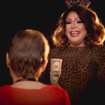 Color photograph taken by Chris Attig Blue Bus Photos showing Arkansas Drag Queen Savvy Savant performing during an intermission at the 2023 Miss Gay Central Arkansas America Drag Pageant in Conway, Arkansas.