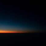 Color photograph taken by arkansas drag photographer Chris Attig showing orange and red first light during sunrise from airplane over arkansas