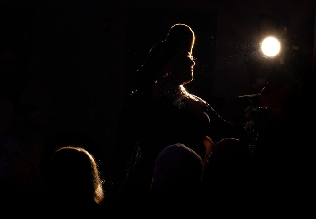 Color photograph taken by Chris Attig Blue Bus Photos showing Arkansas Drag Queen Melanie Masters first alternate Miss Gay Arkansas America 2021 performing drag during an entertainment intermission at the 2023 Miss Gay Central Arkansas America Drag Pageant in Conway, Arkansas.
