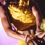 color image of of Little Rock Arkansas Drag Queen Aubi Gold performing in a yellow top at Diamonds and Pearls at Club Sway while holding a microphone