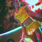 color image of Little Rock Arkansas Drag Queen Aubi Gold performing in a yellow top and white feathered wings at Diamonds and Pearls at Club Sway in a yellow skirt and top