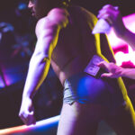 color image of Little Rock Arkansas Drag go go dancer Ed Gates performing at intermission of Diamonds and Pearls at Club Sway in a yellow skirt and top