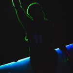 color image of Little Rock Arkansas Drag Queen Envy S. Hart in silhouette with a green outline from the spotlight at Diamonds and Pearls at Club Sway