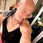 selfie of Little Rock Queer photographer Gynger in Little Rock Arkansas wearing a pink midi pencil skirt and a backless crochetted halter top with tassles and pink glasses