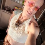 Queer photographer Gynger St Clair from Little Rock Arkansas poses in her ex mother in law's beautiful over-sized wooden necklace