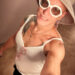 Queer photographer Gynger St Clair from Little Rock Arkansas poses for a selfie while wearing a whit spaghetti strap tank top
