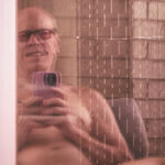 Little Rock Arkansas Trans woman and queer photographer Gynger St Claire takes a selfie in a reflection as she sits idle on her patio one early morning