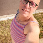 little rock arkansas trans woman queer photographer Gynger St Clair poses for a selfie while walking whearing a pink, orange and purple crop top cami and a black mini skirt.